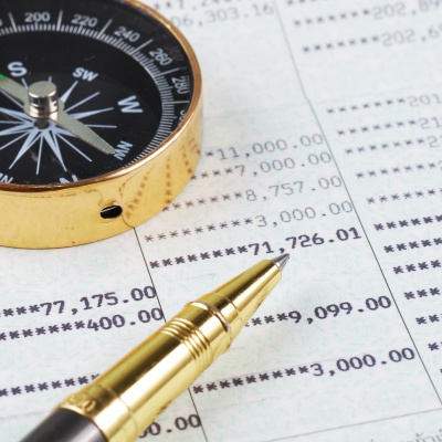 A compass and a pen lie on a printout with tax-related figures. Let us prepare your tax return and be your tax law compass.